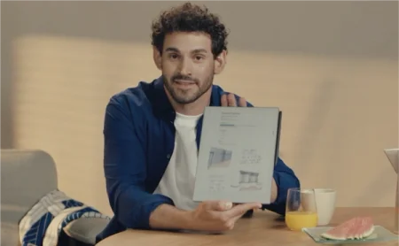 A man sitting at a table holding a reMarkable Paper Pro.